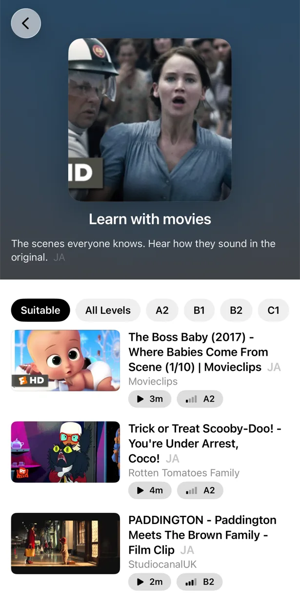 PlayLingo catalog on iPhone: the “Learn with movies” collection with level chips (Suitable, All Levels, A2, B1, B2, C1) and a CEFR level badge on every video.